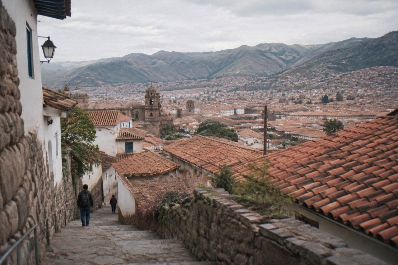Terracotta rooftops of a high Andean city spreading across a valley below distant mountains