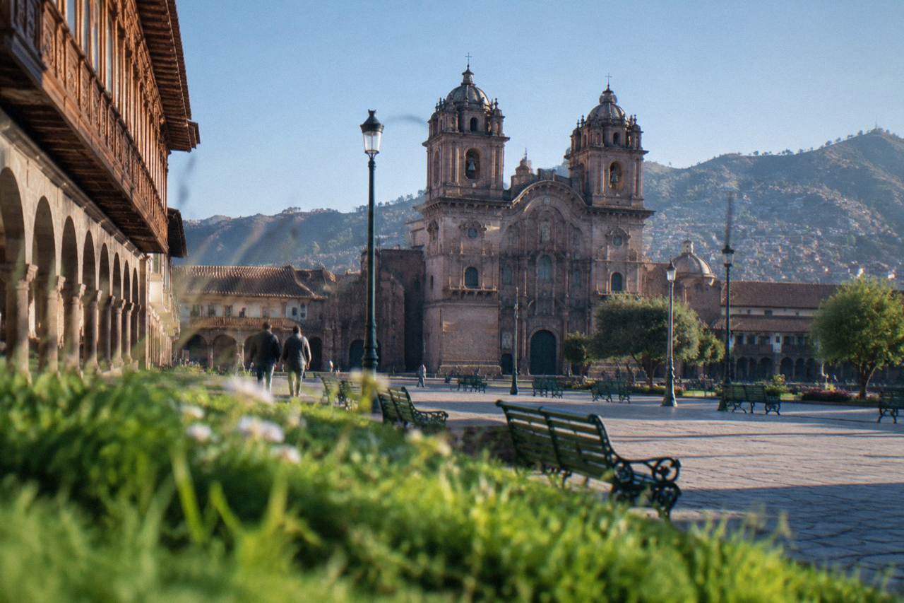 Colonial arcades and stone walls around a plaza in Cusco, Peru, under a clear sky