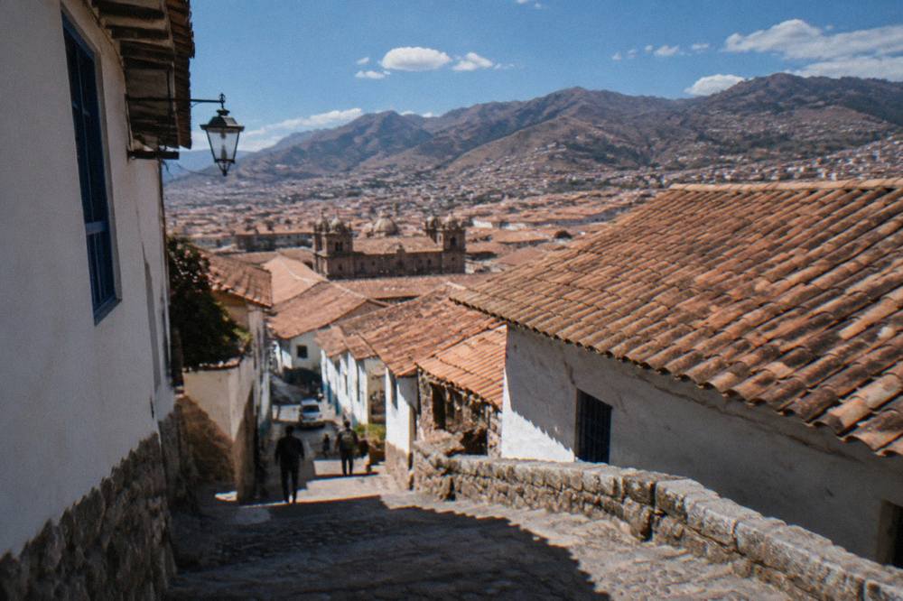 Terracotta rooftops of Cusco spreading across a hillside with mountains behind