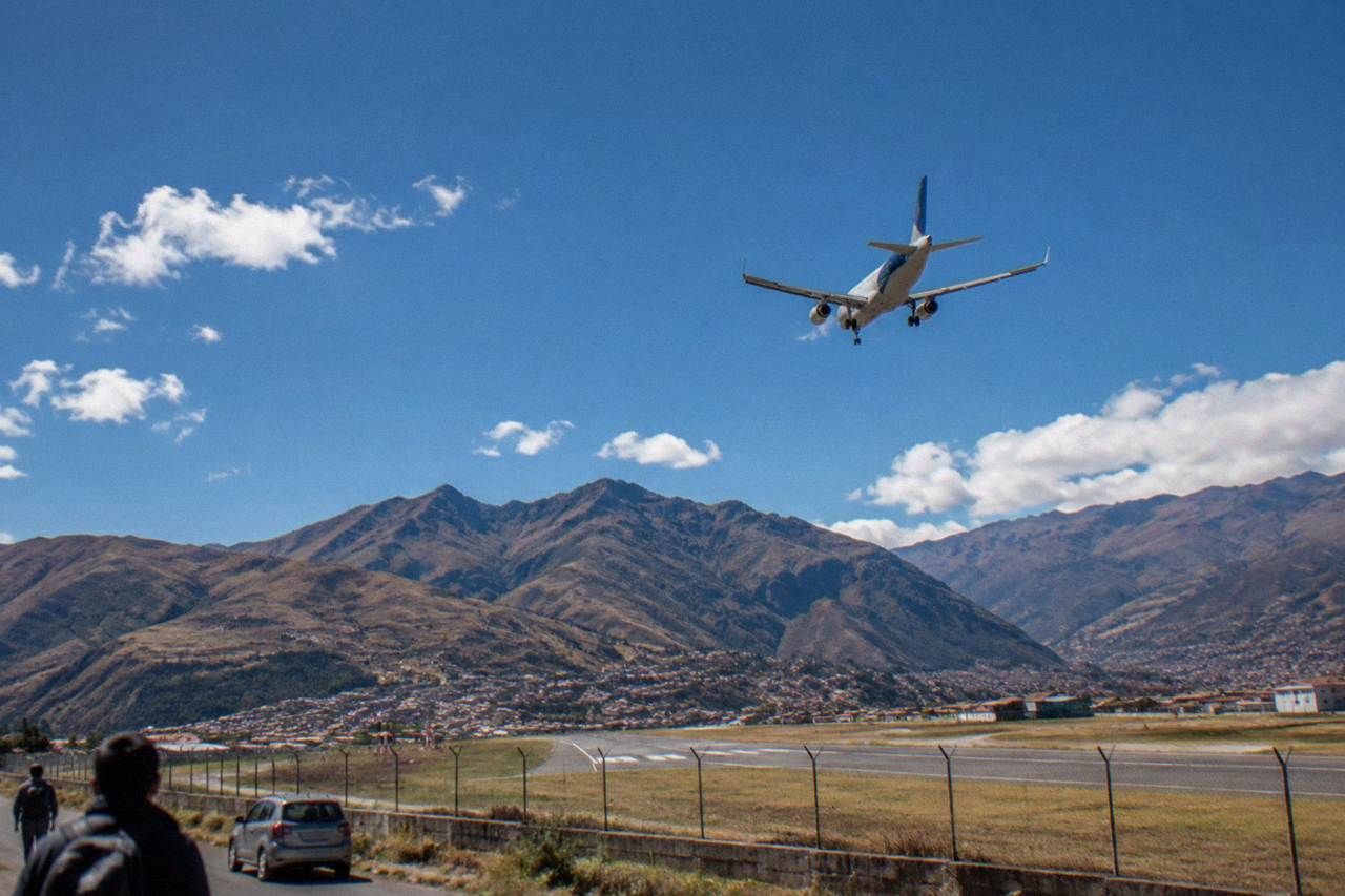 A plane descending over Andean mountains toward a small city airport in a high valley
