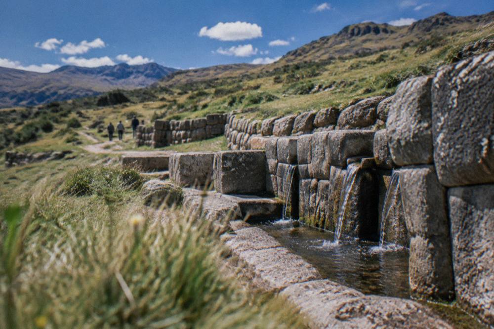 A stone water channel at Tambomachay with the high Andean grassland behind it