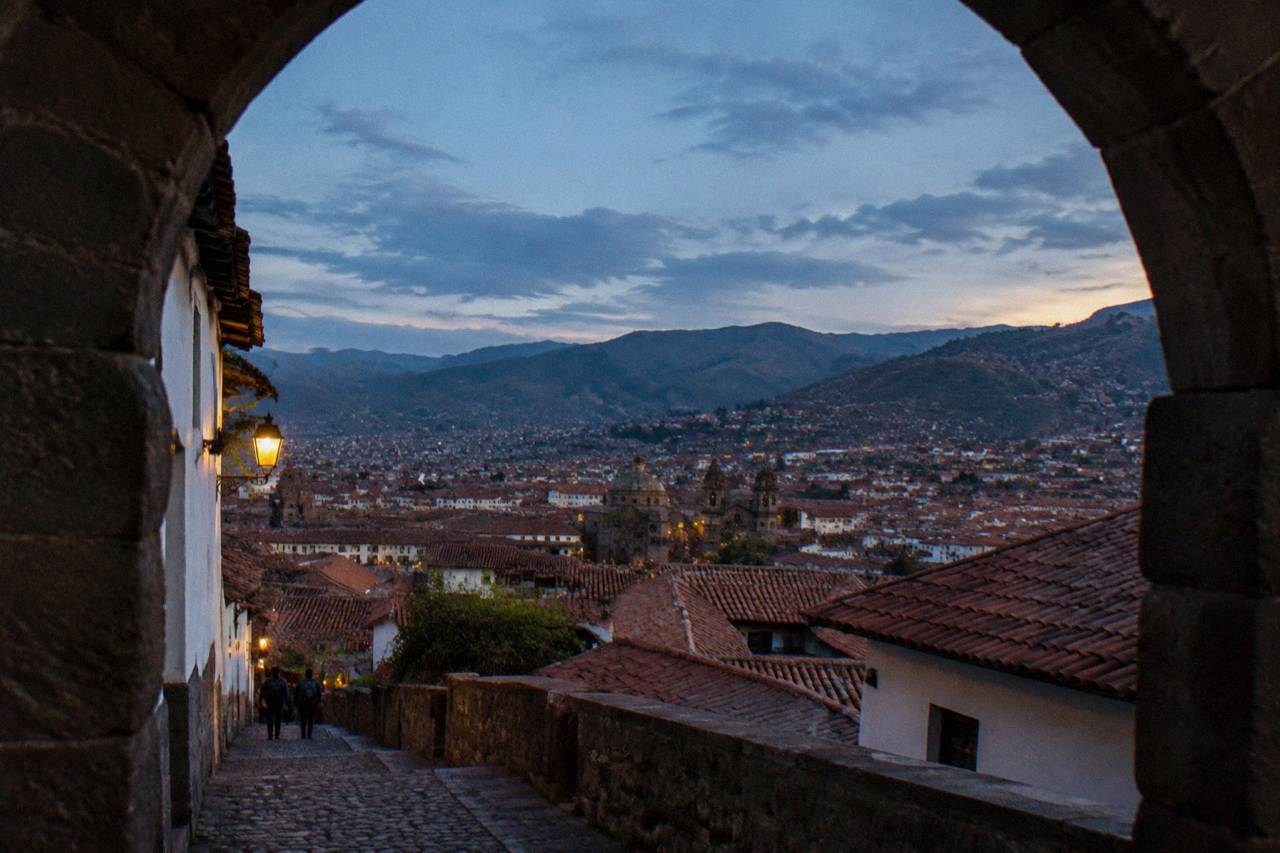 Red tiled rooftops of Cusco spreading across a high Andean valley under a wide blue sky