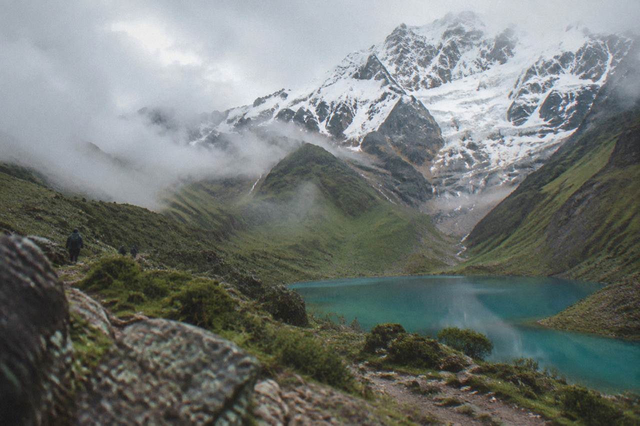 A turquoise mountain lake sitting below a snow-covered peak in the Andes