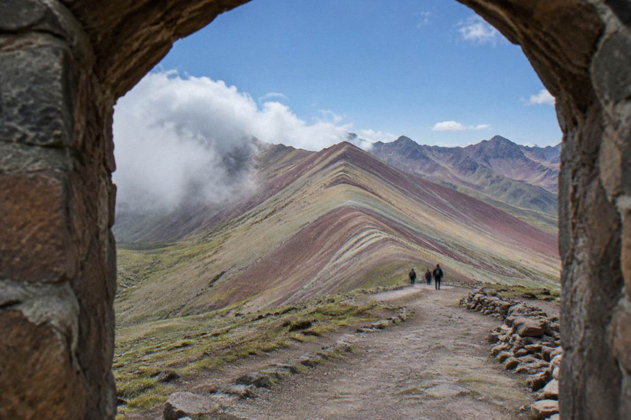 A high Andean valley with striped mineral slopes and a small stone trail under a clear sky