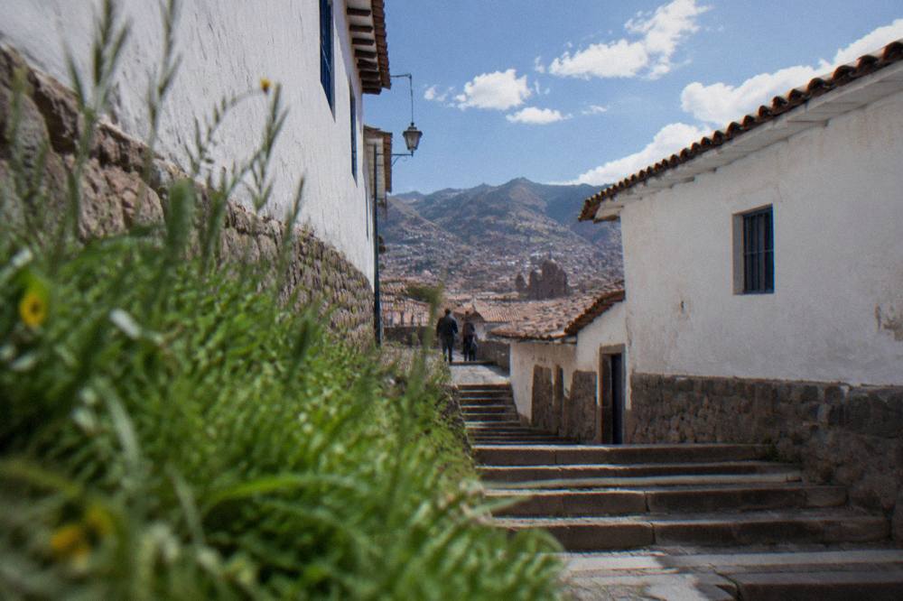 A stone staircase between whitewashed walls leading up through a Cusco neighbourhood