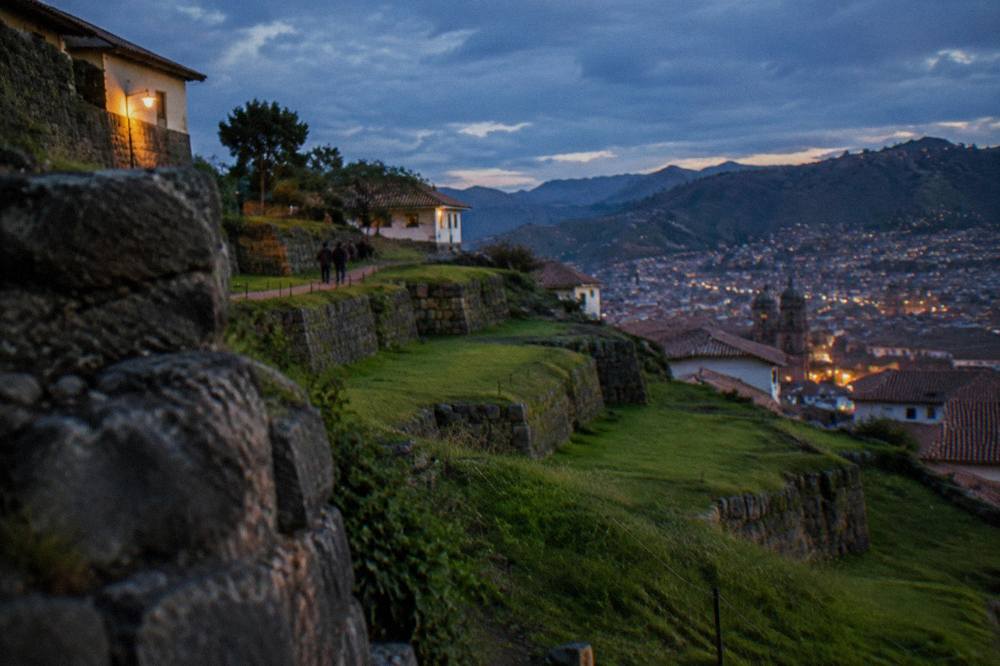 Terraced Inca stonework on a green hillside above Cusco under afternoon light