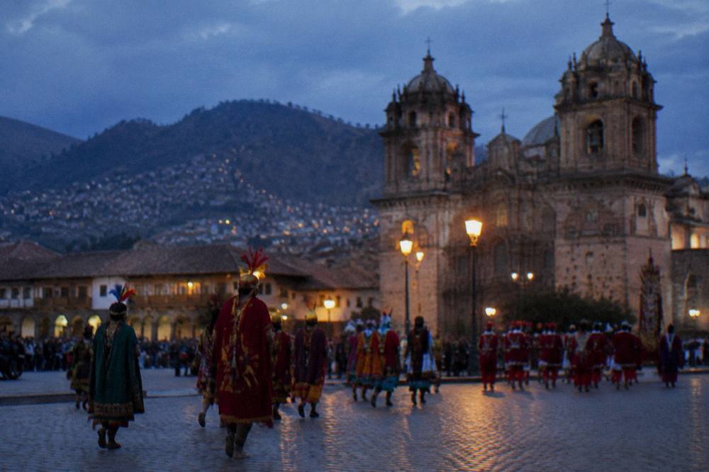 A procession of costumed participants crossing Cusco's main square