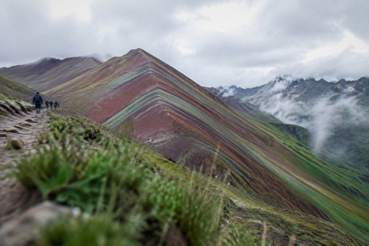 A striped red and green Andean mountain ridge under a wide high-altitude sky