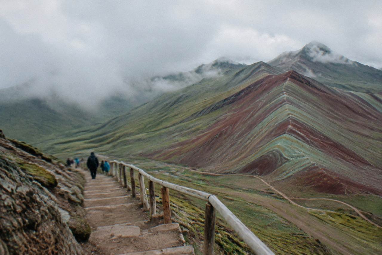 Striped red and green slopes of a high Andean mountain under a wide sky
