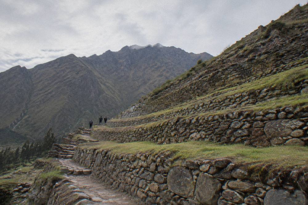 Stone agricultural terraces climbing a hillside with mountains behind