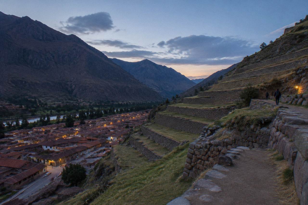 Terraced Inca stone walls rising above the red rooftops of Ollantaytambo under a bright Andean sky