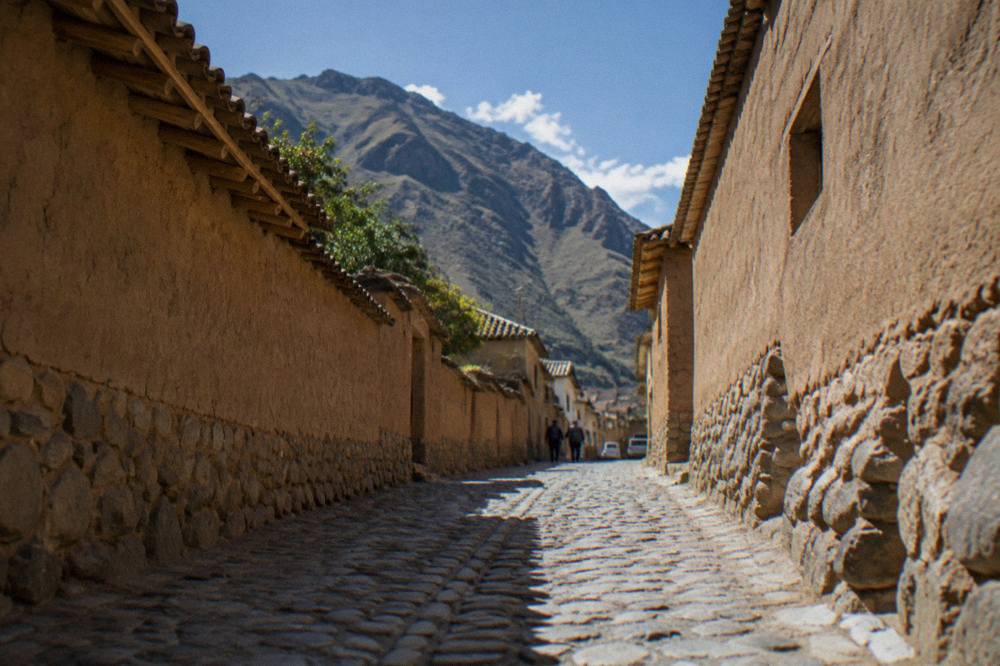 A cobbled lane between adobe walls in Ollantaytambo's old town in early morning light