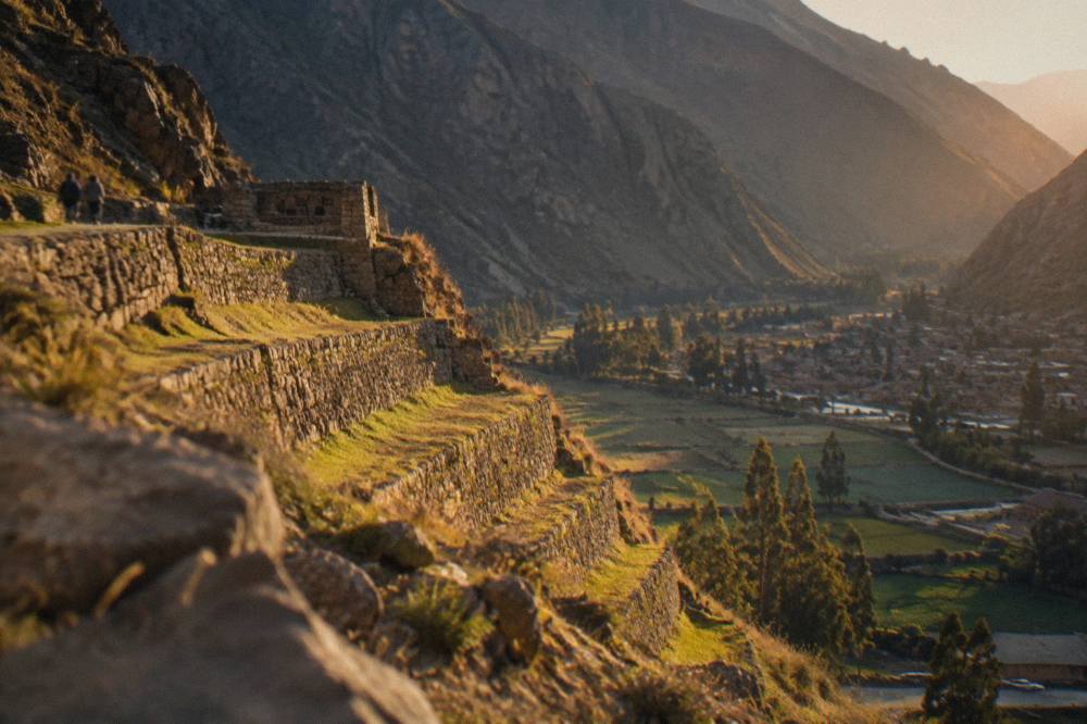 Terraced hillsides above Ollantaytambo with stone agricultural terraces and valley fields below