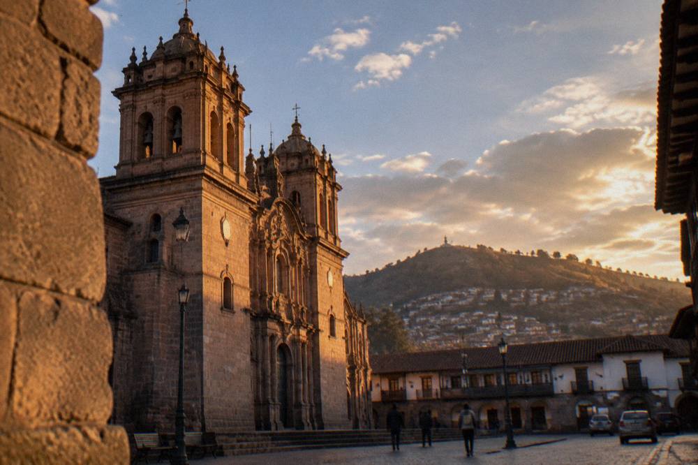 A street in Cusco's historic centre with stone walls and a hillside behind the rooftops