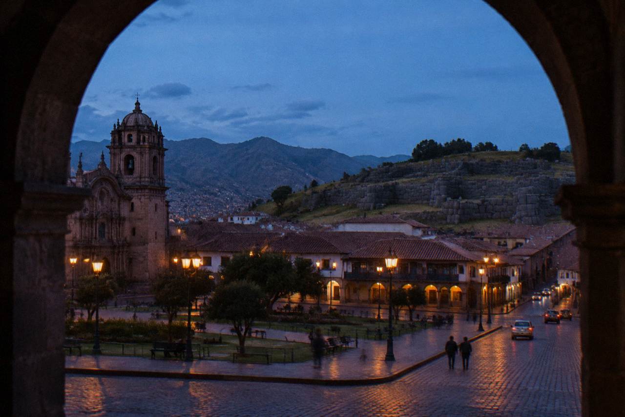 Stone terraces of Sacsayhuaman on a hillside above the red rooftops of Cusco under a blue sky