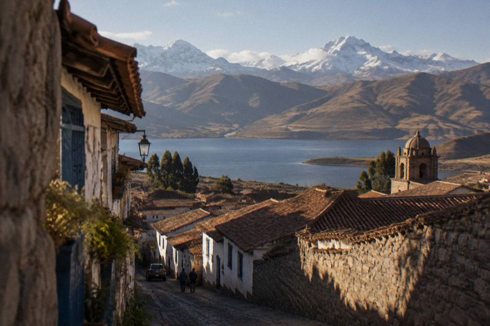 A high Andean lake below snow-covered peaks under a bright morning sky