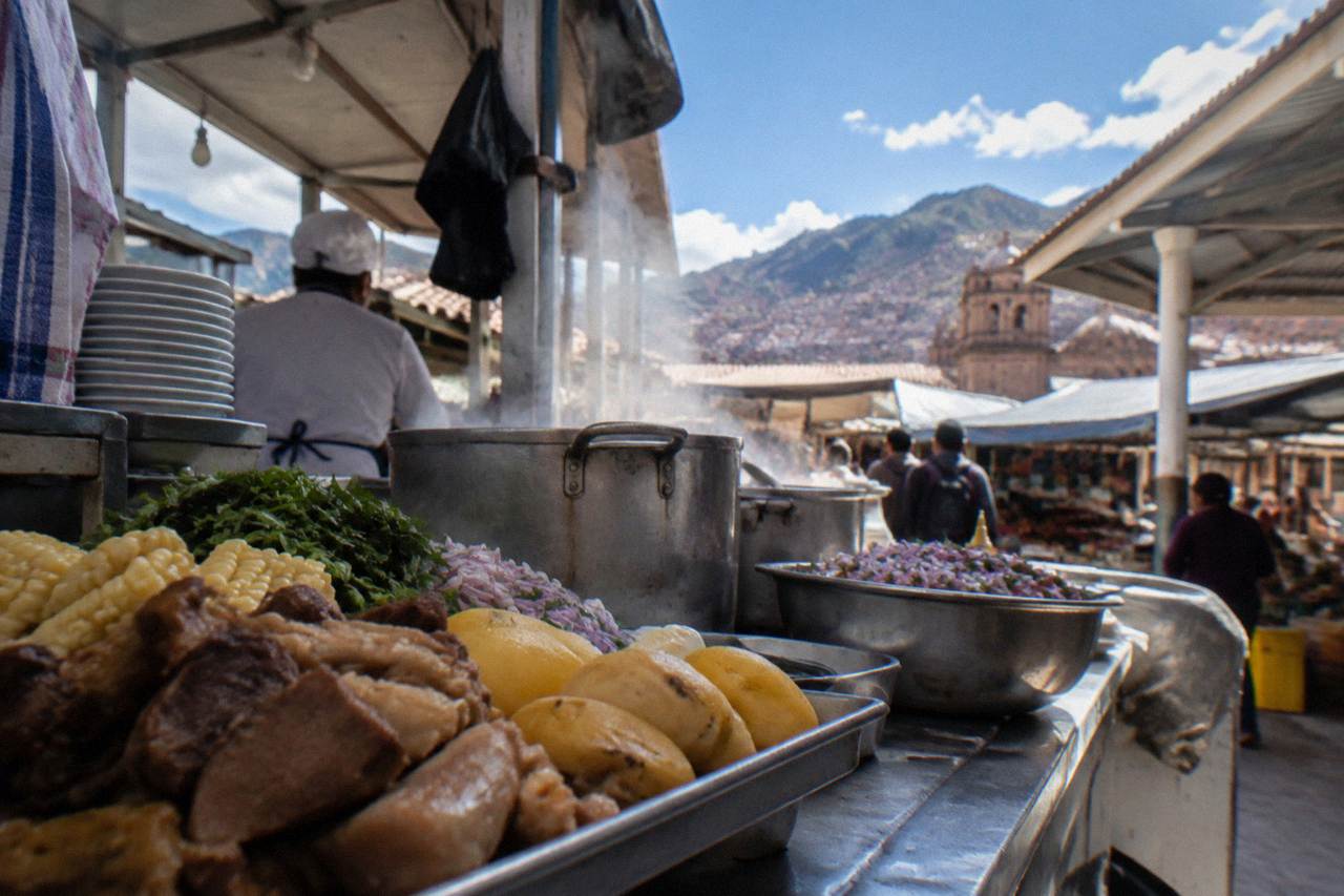 A busy food stall counter in a Cusco market with steam rising from cooking pots