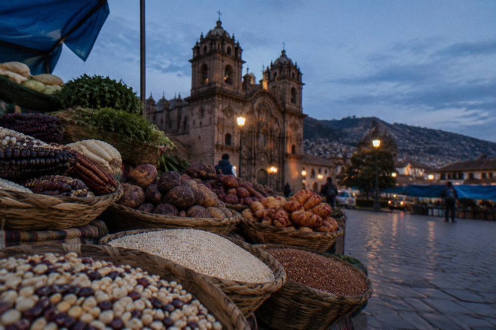 Andean grains and fresh produce piled in baskets at a Cusco market stall