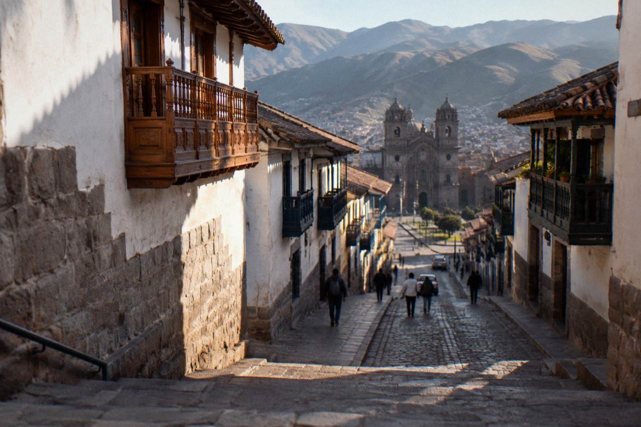 A narrow stone-paved street in the historic centre of Cusco with colonial balconies above