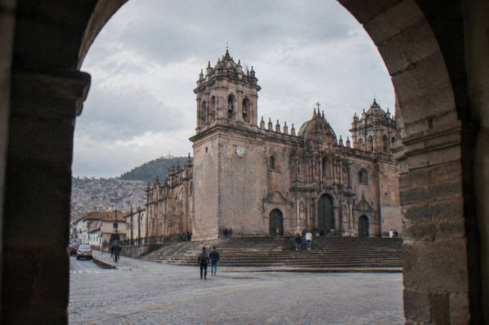Narrow cobblestone street with an Inca stone wall rising beside a colonial building