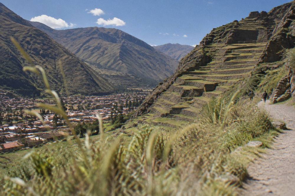 Stone terraces of an Inca site rising above a small valley town