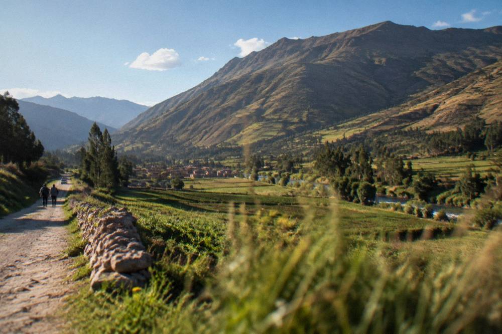 Green valley fields beneath a mountain with late afternoon light
