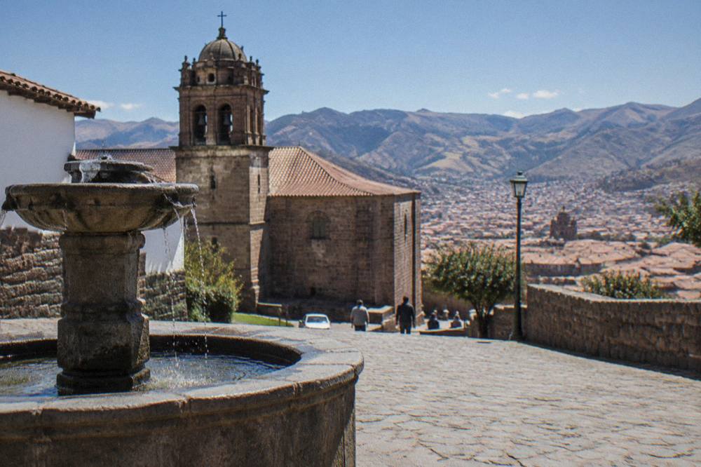 A sunny afternoon on a cobblestone lane with a stone fountain and clear sky