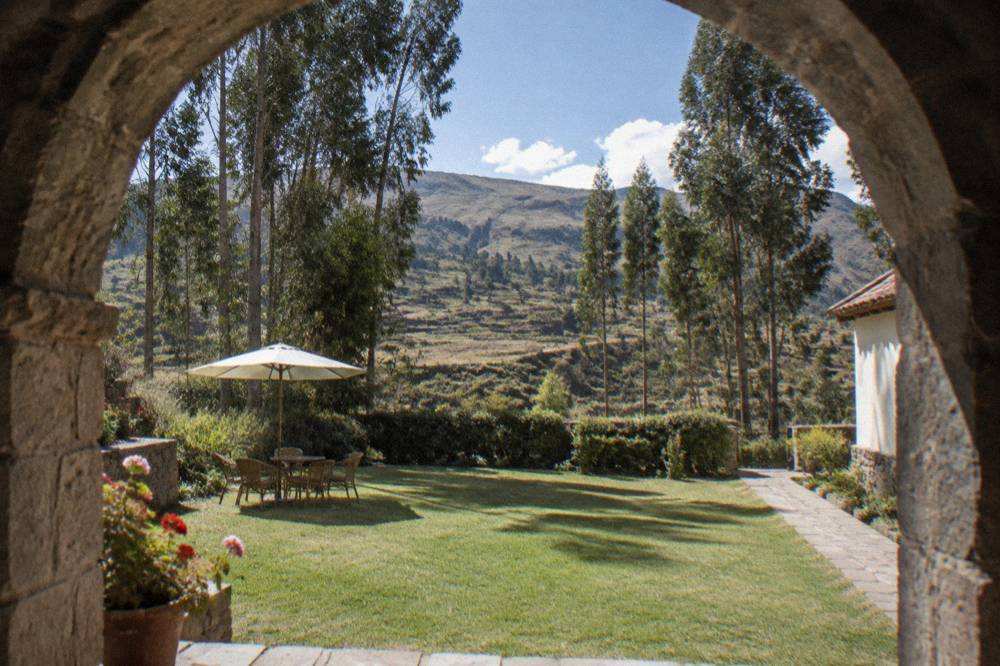 A guesthouse garden with eucalyptus trees and terraced hills behind