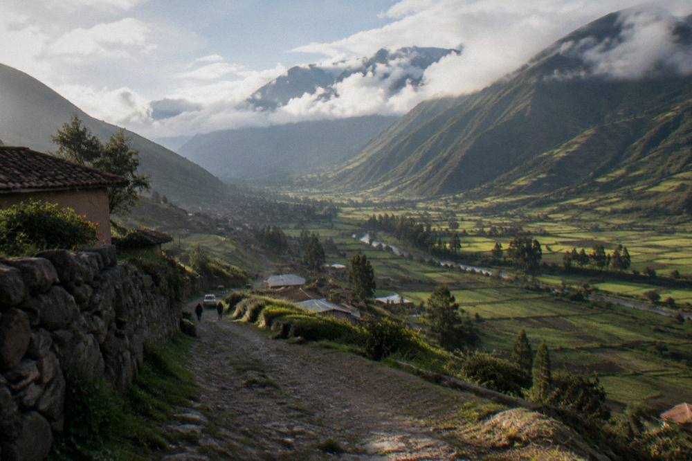 Rain clouds drifting over green valley slopes with patchwork fields