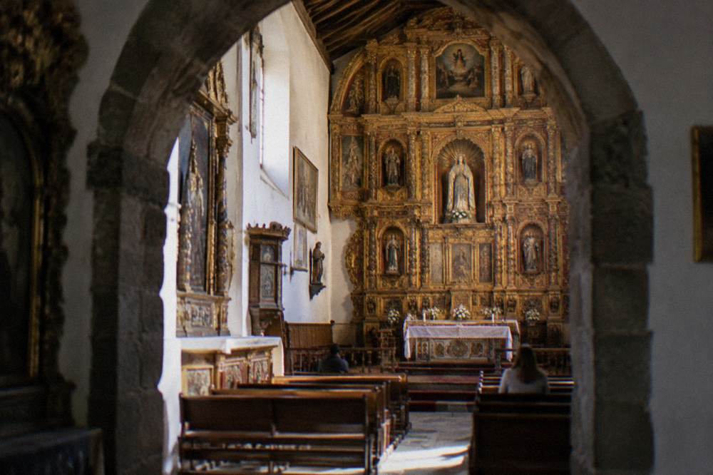 A gilded carved altarpiece inside a colonial Andean church lit by soft daylight