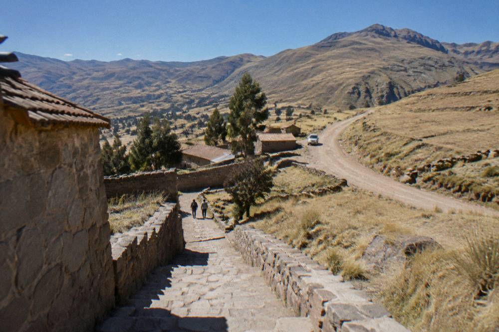 A clear sky over Andean hills with dry grass and a dirt road