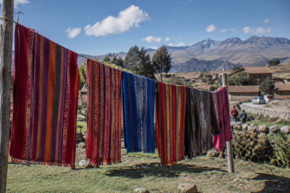 Handwoven textiles in bright colours hanging on a line in the Andes