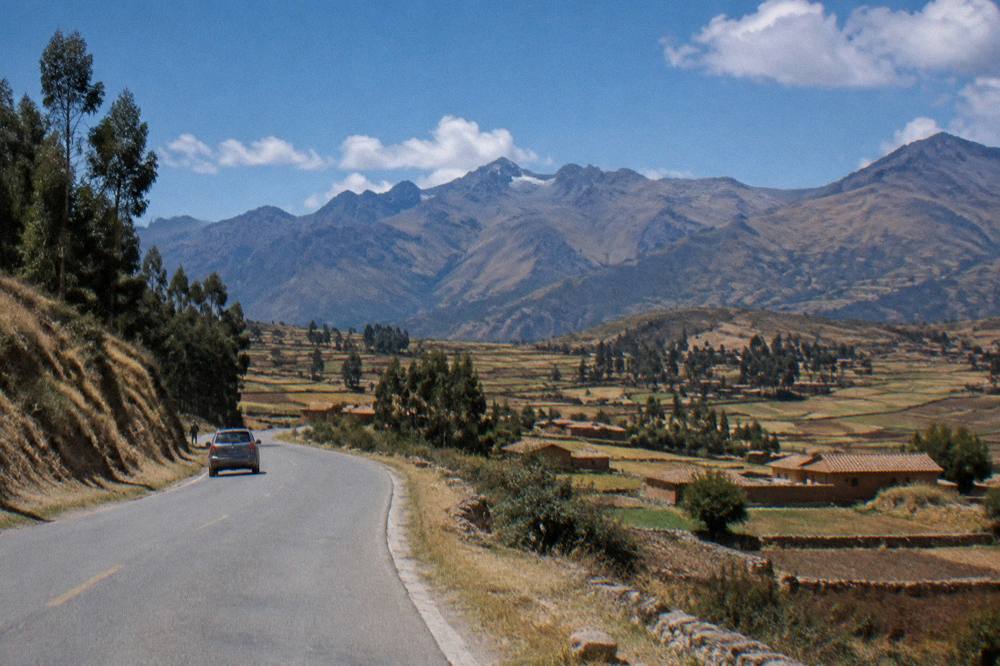 A high plateau road above the Sacred Valley with fields and adobe houses