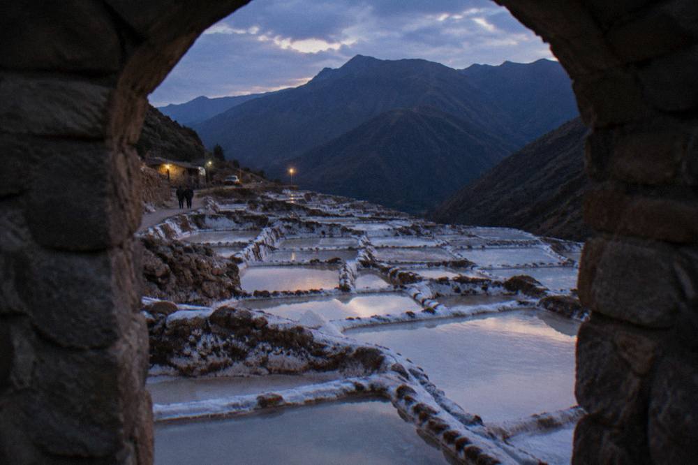 Close view of shallow rectangular salt ponds with white salt crusts and mud walls near Maras