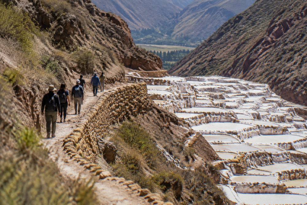 Group of visitors walking the path above the salt terraces with a guide