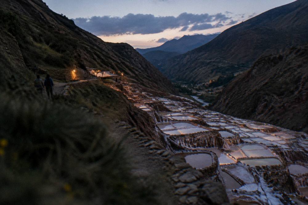 Salt pans terraced into a hillside catching the light in uneven patches