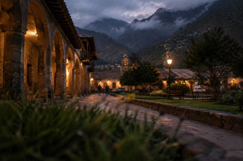 A small town plaza at dusk with hillsides fading into cloud above the rooftops