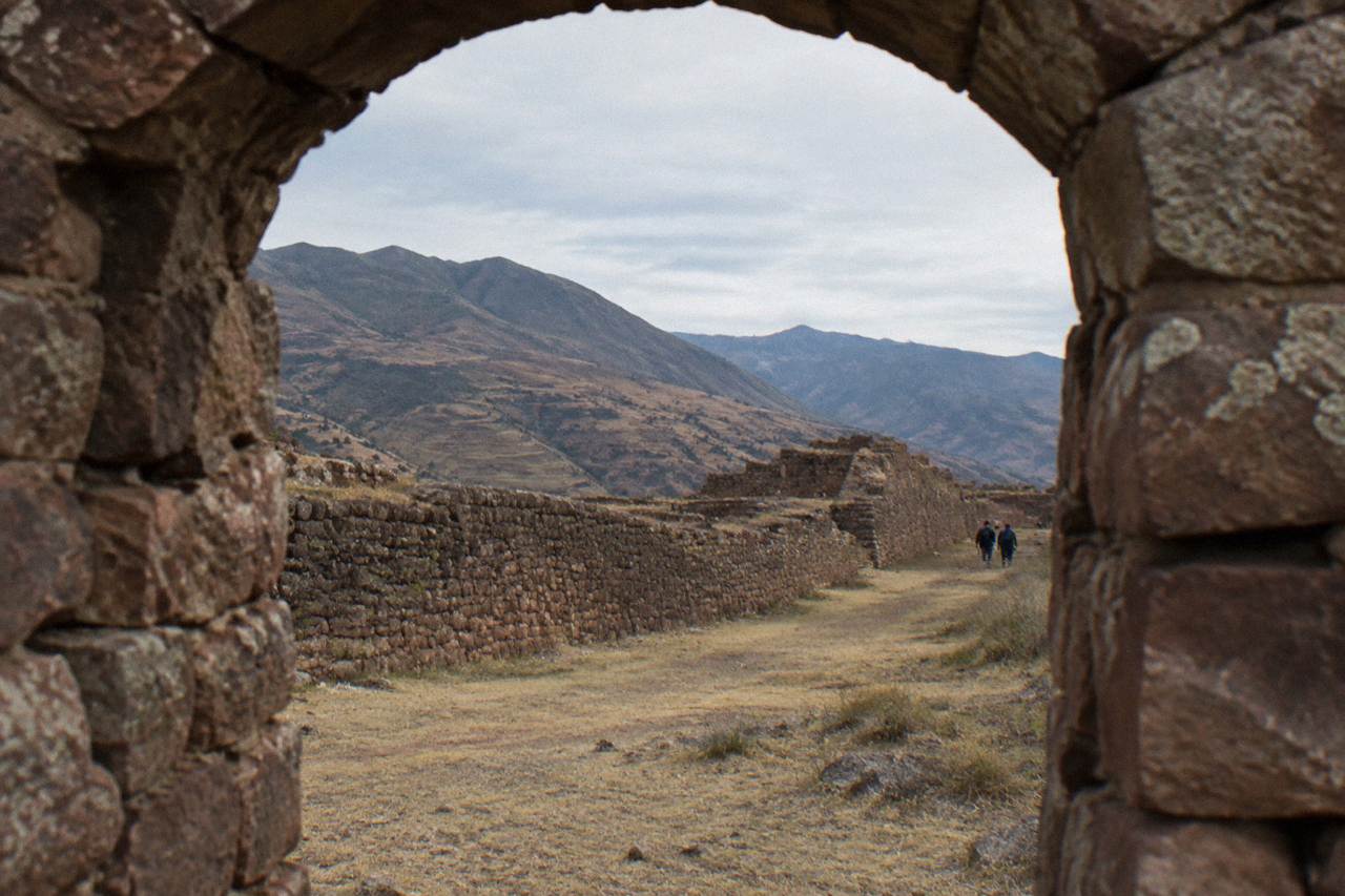 Long stone walls of a pre-Inca site running across a dry valley floor