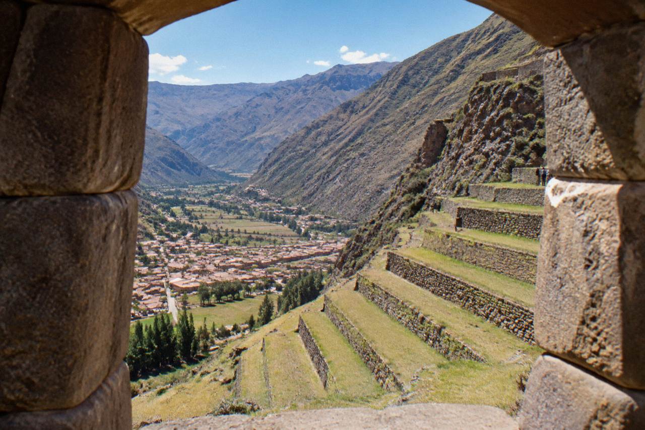 Inca farming terraces stacked down a steep mountainside above a small Andean valley town