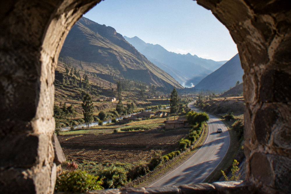 A country road winding along a valley floor between farmed fields and hills