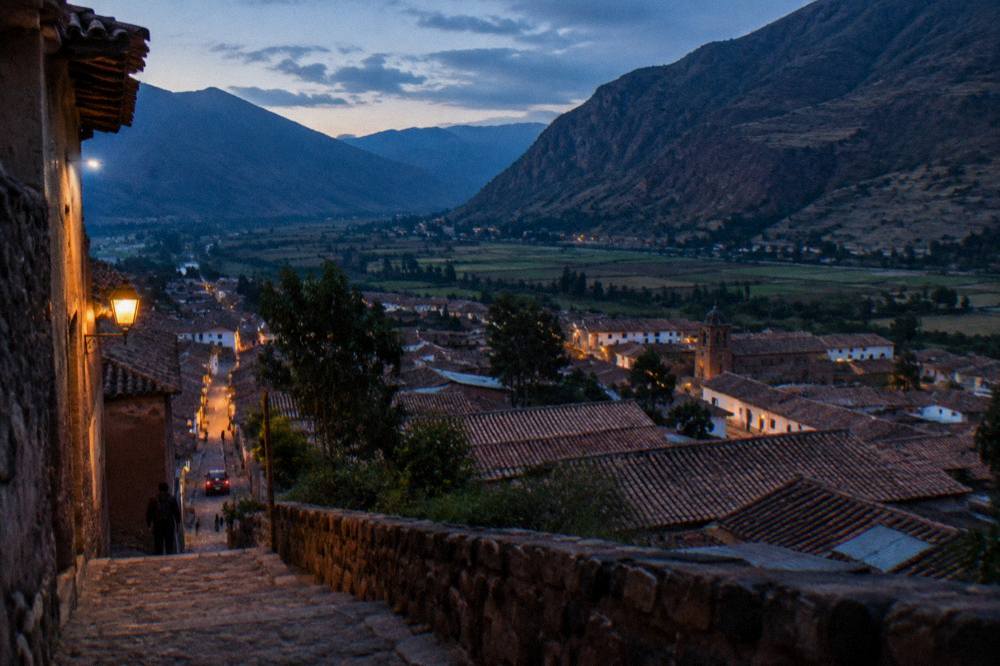 A wide view of a Sacred Valley town with farmland and mountains behind it
