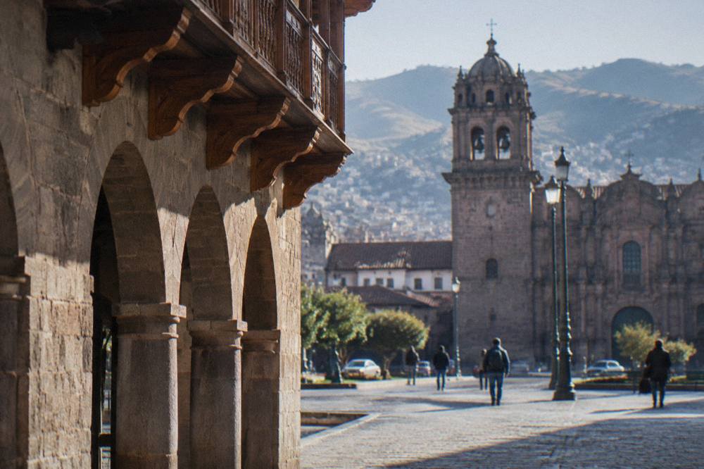 Tourists and local residents crossing the stone plaza between the cathedral and the arcades