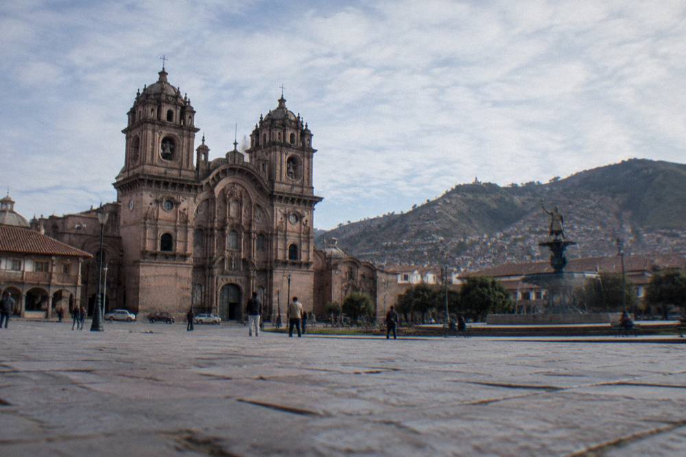 The wide stone square under a clear sky with the cathedral towers and surrounding hills in view