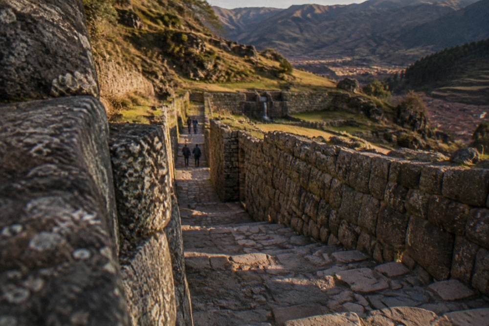 A stone stairway and walled passage climbing through an Inca site on a hillside