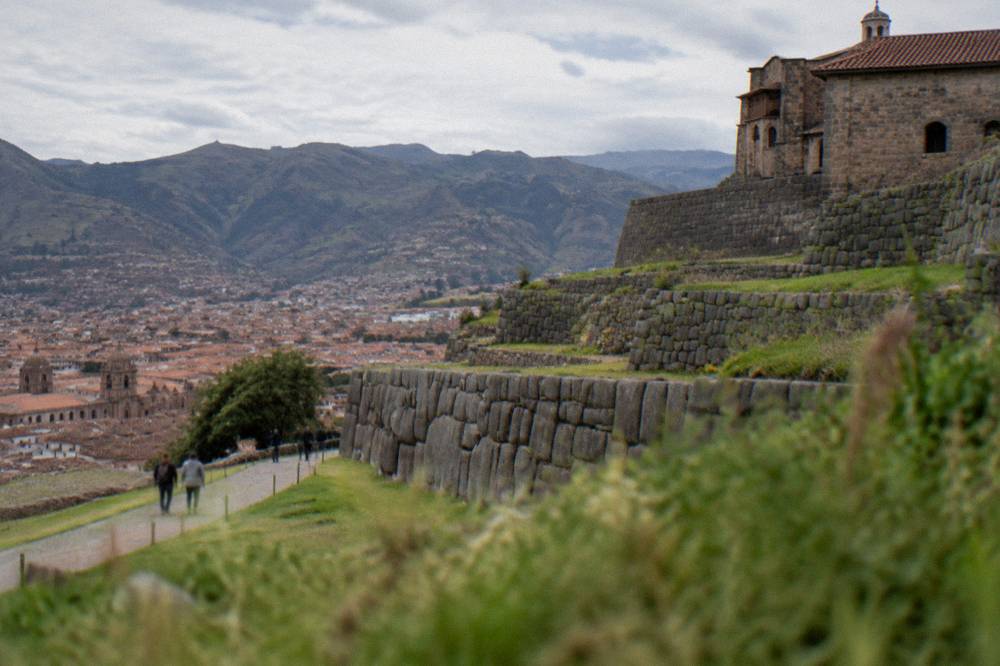 Terraced Inca stonework on a hillside above the red rooftops of Cusco