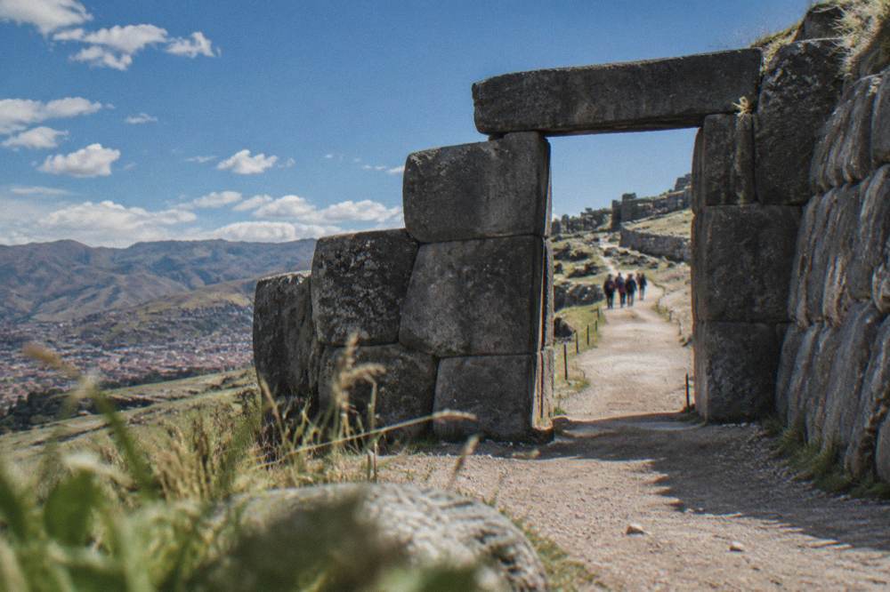 A stone gateway and dirt pathway leading into an archaeological site on a hillside