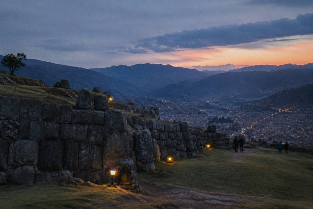 Open hillside above a city with distant mountain ridges at sunrise