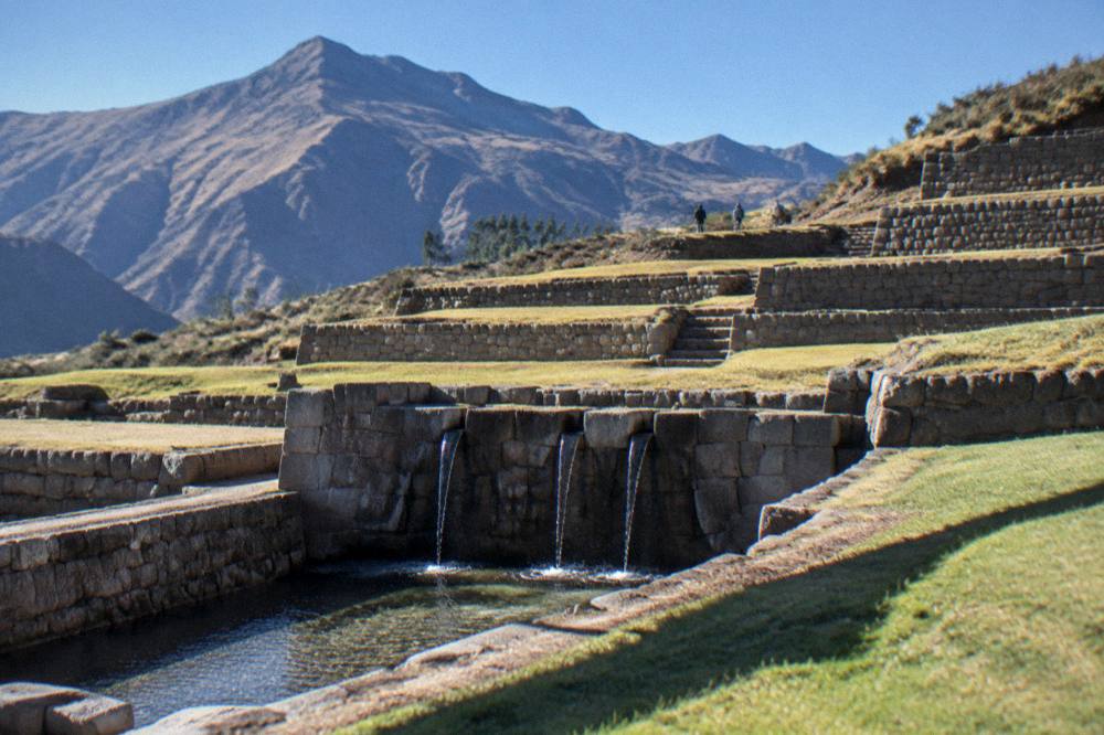 Morning light on stone terraces at Tipon with long shadows and a clear blue sky