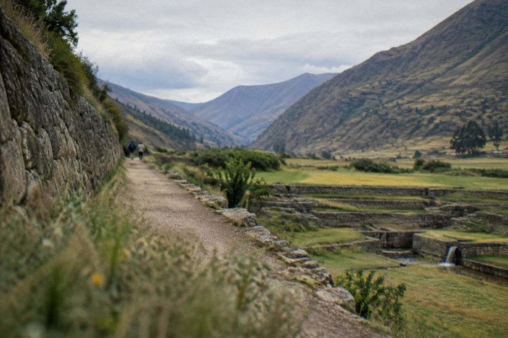 A quiet path along a stone wall at Tipon with the valley opening beyond