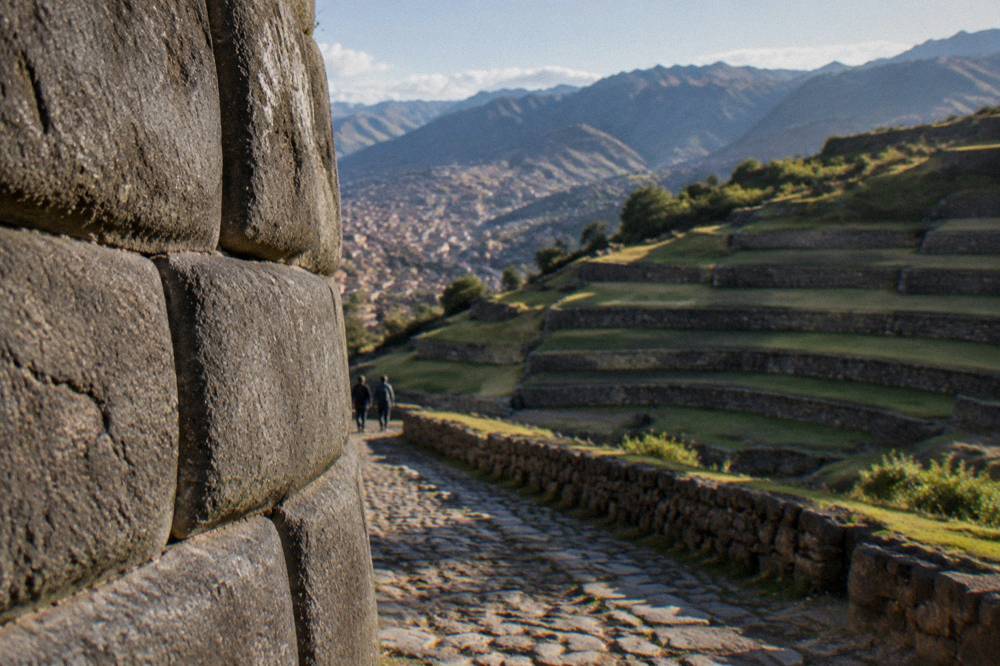 Terraced stone agricultural steps set into a green valley hillside under morning light